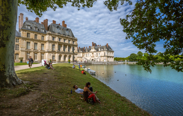 Its steep sloping roofs, the turret-like chimneys, dimensional alcoves, symmetrical arches, rectangular windows, and circular ventilators provide a pleasing look to an otherwise routine facade. - Palace and Park of Fontainebleau, France - Travelure ©