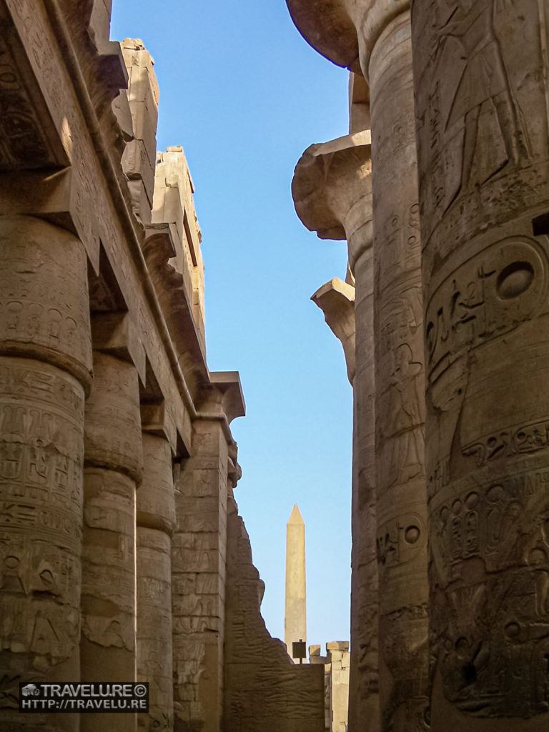 Massive pillars of the processional gallery. A gigantic obelisk forms the backdrop. - Travelure ©