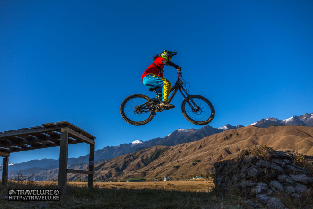 On top of the world! A mountain biker show-jumps past an incline. - Travelure ©