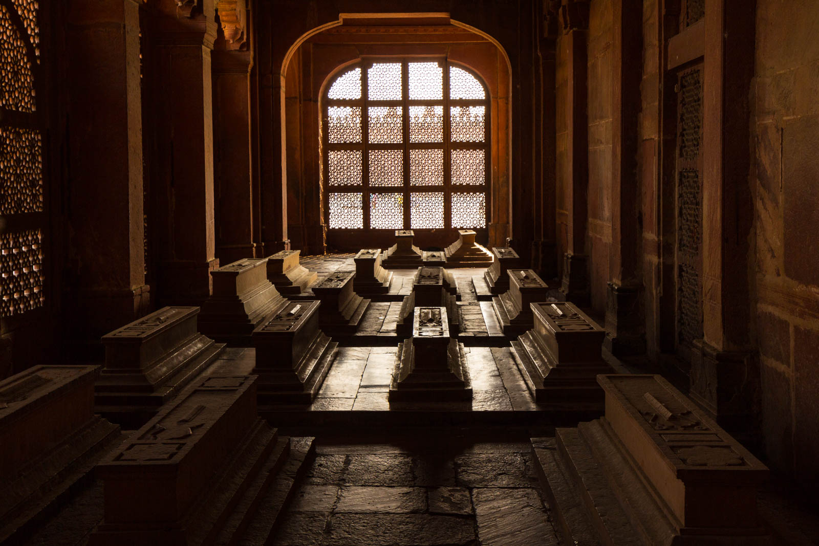 Interior of Fatehpur Sikri with jali screen and cenotaphs in low light, Uttar Pradesh